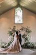 Bride Wearing Princess Wedding Dress Called Norvinia By Sottero And Midgley Kissing Groom Next To A Floral Arrangement