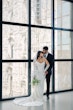 Bride wearing Moon by Maggie Sottero and her husband in front of a window