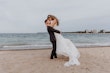 Bride Wearing Beaded Fit-n-flare Wedding Dress Called Jonah Lane By Sottero And Midgley With Groom On The Beach