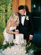 Bride Wearing Simple Fit And Flare Wedding Dress Called Mitchell Marie By Maggie Sottero Cutting The Cake With Groom