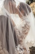 Bride Wearing Crepe And Lace Bridal Dress Called Dionne By Rebecca Ingram Kissing Groom Underneath Her Veil