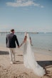 Bride Wearing Off-The-Shoulder Lace Wedding Dress Called Carson By Sottero And Midgley Holding Hands With Groom