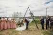 Bride and groom kissing at the altar by the water while wedidng party cheer.