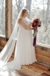 Bride In Chiffon Wedding Dress Called Tasha By Rebecca Ingram With Red And Blue Rose Bouquet 