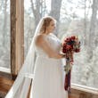 Bride In Chiffon Wedding Dress Called Tasha By Rebecca Ingram With Red And Blue Rose Bouquet