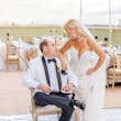 Bride Wearing Lace Mermaid Wedding Dress Called Bronson By Sottero And Midgley Looking At Groom Sitting Down