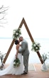 Bride Wearing Simple Chiffon Wedding Dress Called Marta Lynette By Rebecca Ingram Kissing Groom At Ceremony On The Beach