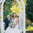 Bride Wearing Sexy Lace Wedding Dress Called Lennon By Maggie Sottero With Groom On A Garden Bench