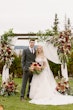 Bride wearing Laila wedding dress by Maggie Sottero at the arch with her husband