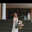 Bride Wearing Simple Fit And Flare Wedding Dress Called Francine By Rebecca Ingram Standing On A Staircase