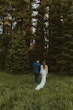 Newlyweds walking towards the woods together. 