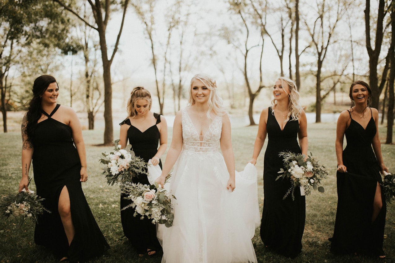 Bride Walking With Bridesmaids Wearing Wedding Gown Called Raelynn by Rebecca Ingram