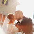 Bride Wearing Lace Long-Sleeve Wedding Gown Called Raphael By Maggie Sottero Kissing Groom