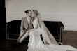 Bride with groom wearing simple sheath wedding dress with V-neck.