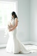 Bride wearing wedding dress called Marquette standing by window.