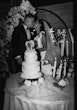 Bride wearing Saratoga by Maggie Sottero kissing her husband by their cake