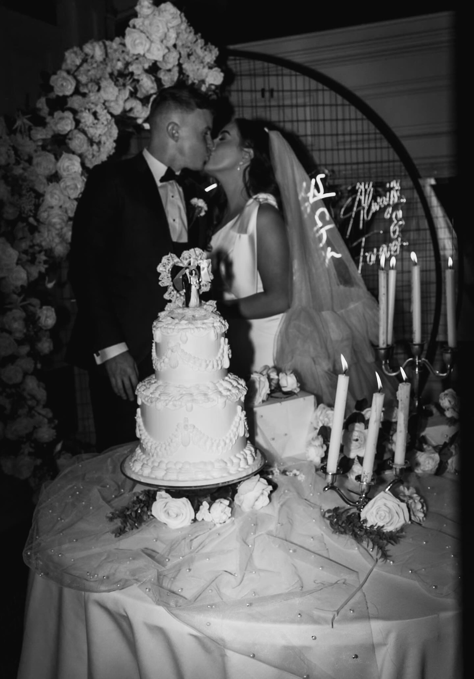 Bride wearing Saratoga by Maggie Sottero kissing her husband by their cake