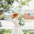Bride Wearing Lace Long-Sleeve Wedding Gown Called Raphael By Maggie Sottero Holding White Rose Bouquet