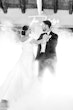 Bride Wearing Off-The-Shoulder A-Line Wedding Dress Called Coral By Rebecca Ingram Dancing With Groom In Fog