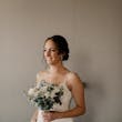 Bride wearing ivory dress holding all ivory bouquet of roses and greenery.