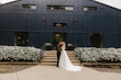 Bride Wearing Aline Satin Wedding Gown Called Scarlet By Maggie Sottero Kissing Groom In Front Of A Black Building