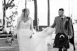 Bride wearing Iris wedding dress by Rebecca Ingram with her husband holding her train