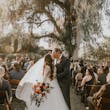 Groom And Bride Share Kiss In Aisle. Bride Wearing Tulle Long Sleeve Ball Gown Called Mallory Dawn By Maggie Sottero