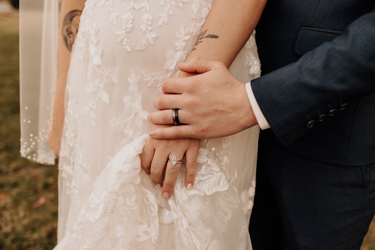 Close up of groom's ring hand on top of the brides.