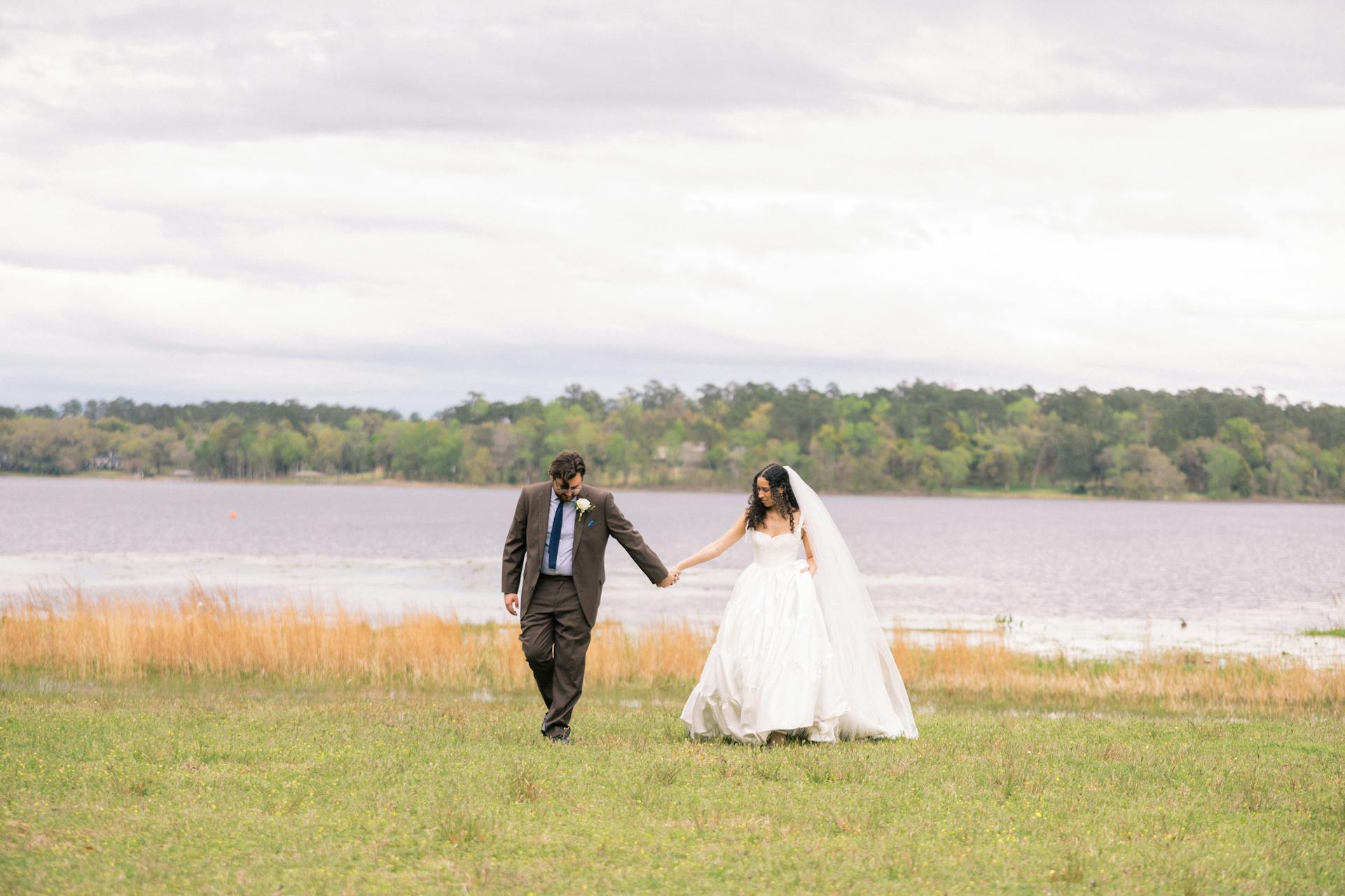 Bride Wearing Aline Ruffled Wedding Dress Called Talitha By Sottero And Midgley Walking With Groom Next To A Lake