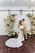 Bride Wearing Lace Fit And Flare Wedding Dress Called Fairchild By Maggie Sottero With Groom Kissing Her Forehead Next To The Flower Arch