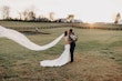 Bride and Groom Kiss With Veil Flowing Behind. Bride Wearing Lace Detailed Halter Wedding Dress Called Kevyn By Sottero And Midgley 