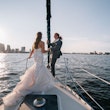 Bride with groom wearing strapless mermaid wedding dress with plunging V-neck.
