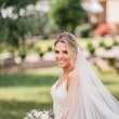 Bride holding pale pink, white and ivory bouquet and flowing veil.