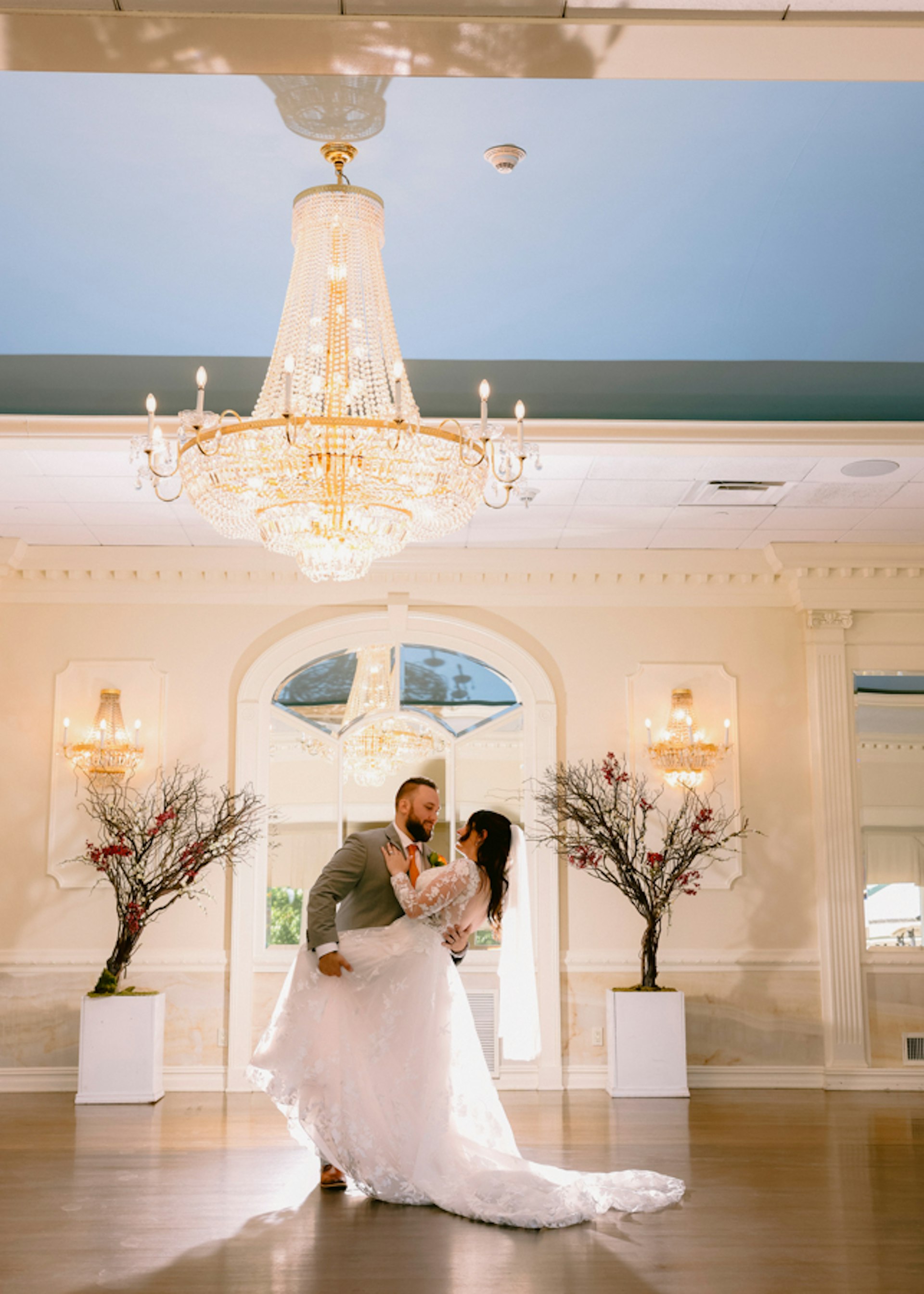 Bride Wearing Lace Long Sleeve Aline Wedding Dress Called Winter By Maggie Sottero With Groom Under A Chandelier