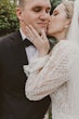 Bride gently kissing groom on the cheek.