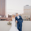 Bride and groom looking at each other with view of buildings behind them.