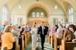 Bride In Satin Simple Wedding Dress Called Alberta By Maggie Sottero With Groom Walking Down Aisle At Church Wedding Venue