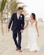 Groom with Bride Walking on Beach Wearing Wedding Dress Called Tuscany by Maggie Sottero.