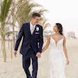 Groom with Bride Walking on Beach Wearing Wedding Dress Called Tuscany by Maggie Sottero.