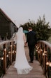 Bride wearing Yates wedding dress by Maggie Sottero walking with her husband over a bridge