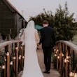 Bride wearing Yates wedding dress by Maggie Sottero walking with her husband over a bridge