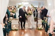 Bride wearing Tuscany Lynette in front of their wedding arch