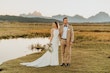 Bride Wearing Keyhole Back Halter Wedding Dress Called Bellarose By Rebecca Ingram With Groom Next To A Pond