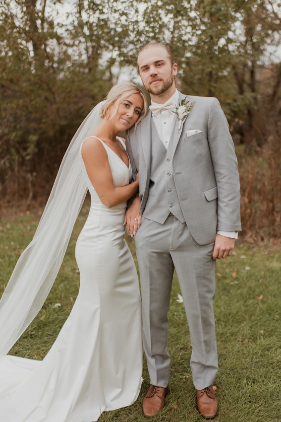 Bride with groom wearing simple sheath wedding dress with V-neck.