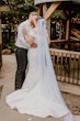 Bride Wearing Simple Fit And Flare Wedding Dress Called Josie By Rebecca Ingram Kissing Groom