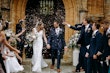 Confetti throw outside church. Bride and groom looking at each other laughing.