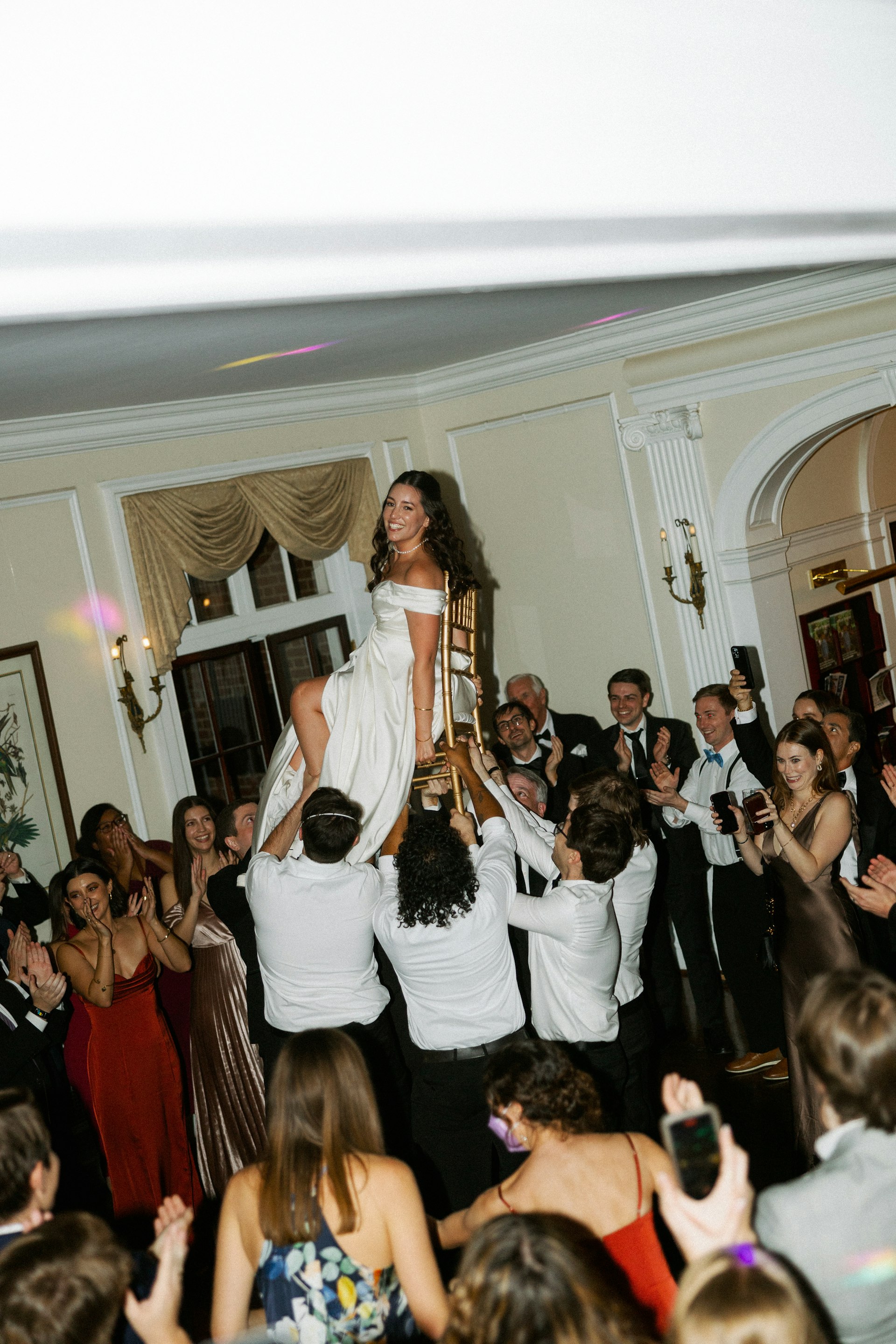 Bride Wearing Satin Aline Wedding Dress Called Ekaterina By Maggie Sottero Being Lifted Up On A Chair