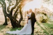 Bride Wearing Off-The-Shoulder A-Line Wedding Dress Called Coral By Rebecca Ingram Kissing Groom