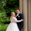 Bride and Groom Next to Tall Columns Wearing Wedding Dress Called Mallory Dawn by Maggie Sottero