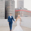 Bride and groom on a rooftop in the city laughing together.